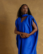 Load image into Gallery viewer, Woman wearing a blue dress against a brown background