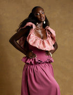 Load image into Gallery viewer, Woman wearing a pink dress with ruffled top against a brown background