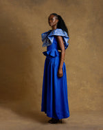 Load image into Gallery viewer, Woman wearing a blue dress with ruffled top against a brown background