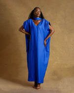Load image into Gallery viewer, Woman wearing a blue dress against a brown background