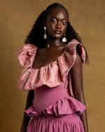 Load image into Gallery viewer, Woman wearing a pink ruffled top and dress against a gold background
