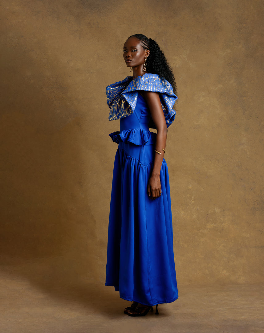 Woman wearing a blue dress with ruffled top against a brown background