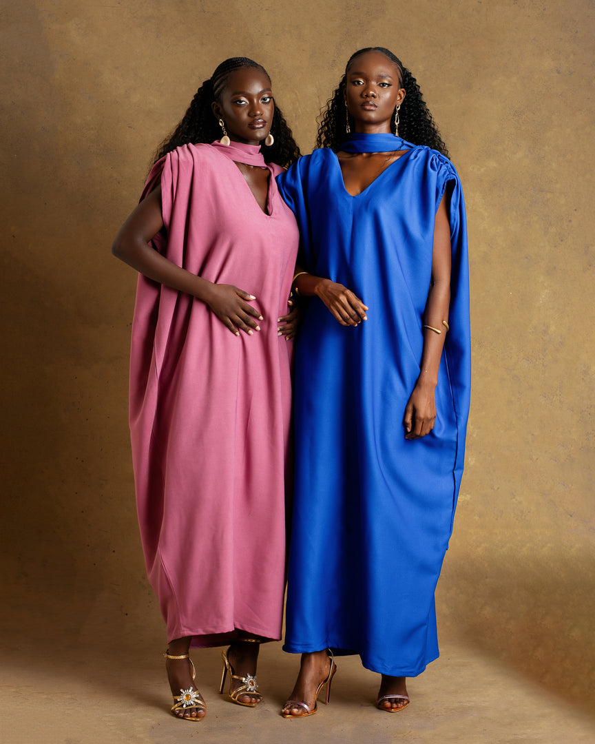 Two women wearing pink and blue dresses against a brown background