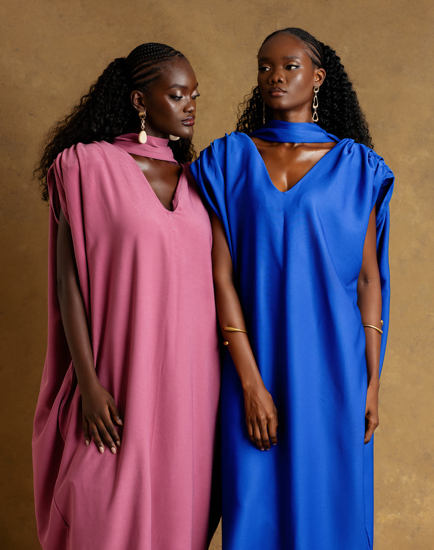 Two women wearing pink and blue dresses against a brown background